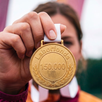 Medaglia d'oro con logo Laborfonds e il numero 150.000 incisi